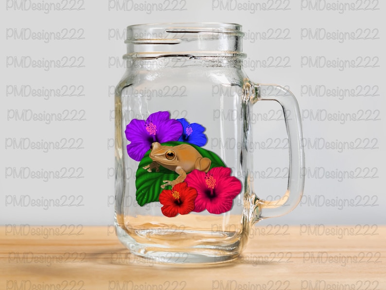 May include: A clear glass mason jar mug with a handle. Inside the mug is a brown frog sitting on a green leaf with red, purple, and blue hibiscus flowers.