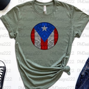 May include: A green t-shirt with a circular design featuring the Puerto Rican flag. The flag is surrounded by a white pattern.