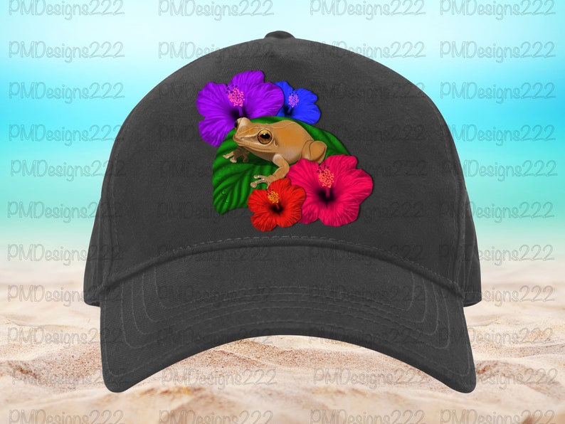 May include: A black baseball cap featuring a brown frog perched on a bed of green leaves and colourful hibiscus flowers. The flowers are purple, pink, and red.