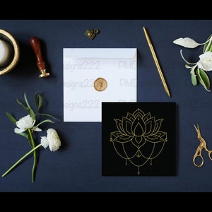Puede incluir: Composici&oacute;n plana con un dise&ntilde;o de flor de loto dorada sobre un cuadrado negro, un sobre blanco con un sello dorado, un bol&iacute;grafo dorado y unas tijeras doradas. Flores blancas y una vela en un cuenco dorado tambi&eacute;n presentes, todo sobre una superficie azul oscuro.