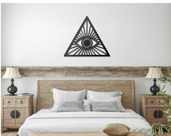 May include: A black wooden wall hanging in the shape of a triangle with an eye inside. The wall hanging is above a wooden bed with white bedding and a wooden bench in front of it.