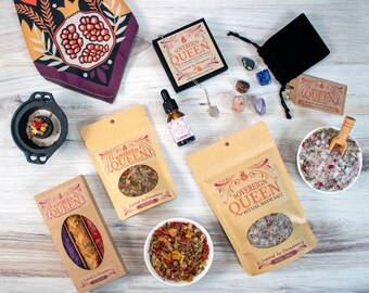 May include: A collection of bath and body products with a pomegranate theme. The products include bath salts, incense, candles, and essential oil. The packaging is brown with gold lettering and features a pomegranate design. The products are arranged on a wooden surface.
