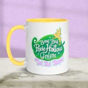 Puede incluir: Taza de cerámica blanca con borde amarillo. La taza presenta un diseño de hoja verde con el texto "Bring Back Pixie Hollow Online That Shit Slapped".