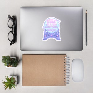 May include: A sticker featuring a crystal ball design with the text "Don't ever let a man tell you about your magic." The crystal ball is light blue and purple, with a decorative purple base. The sticker is on a laptop.