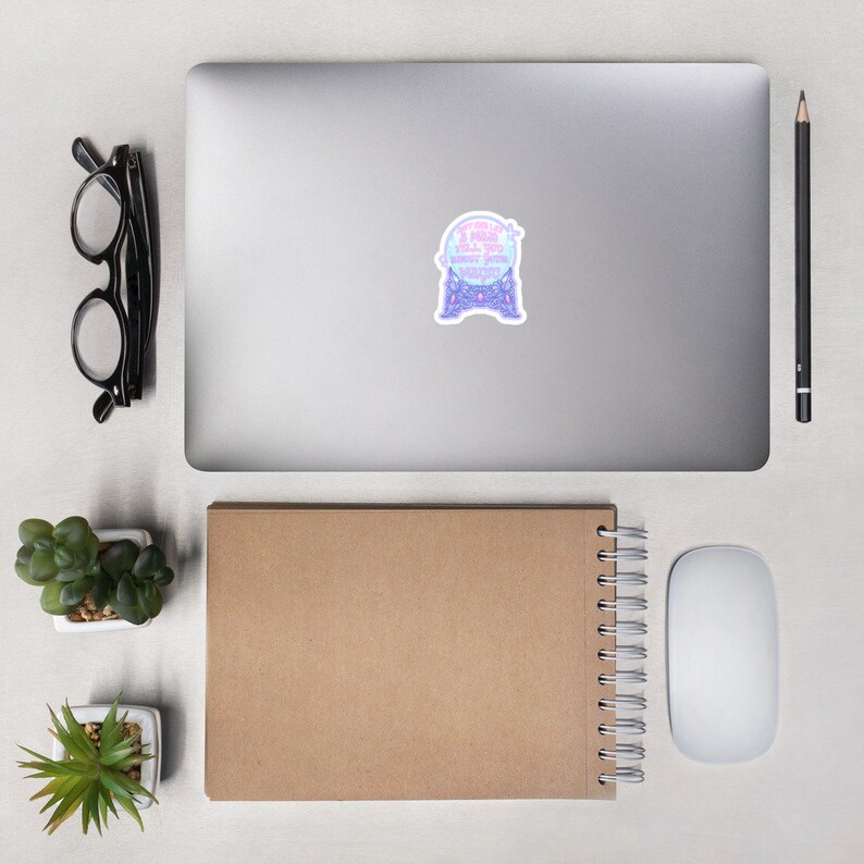May include: A sticker featuring a crystal ball design with the text "I need you to know about your destiny" in pink and blue. The sticker is on a laptop, with glasses, a pencil, and a notebook nearby.