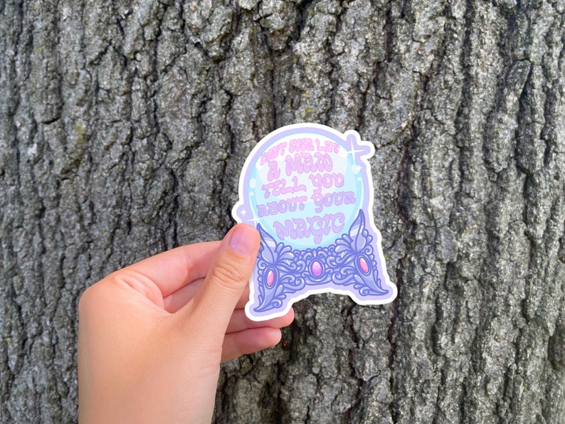 May include: A sticker featuring a crystal ball design with the text "Don't ever let a man tell you about your magic." The sticker has a light purple and blue color scheme with decorative accents.