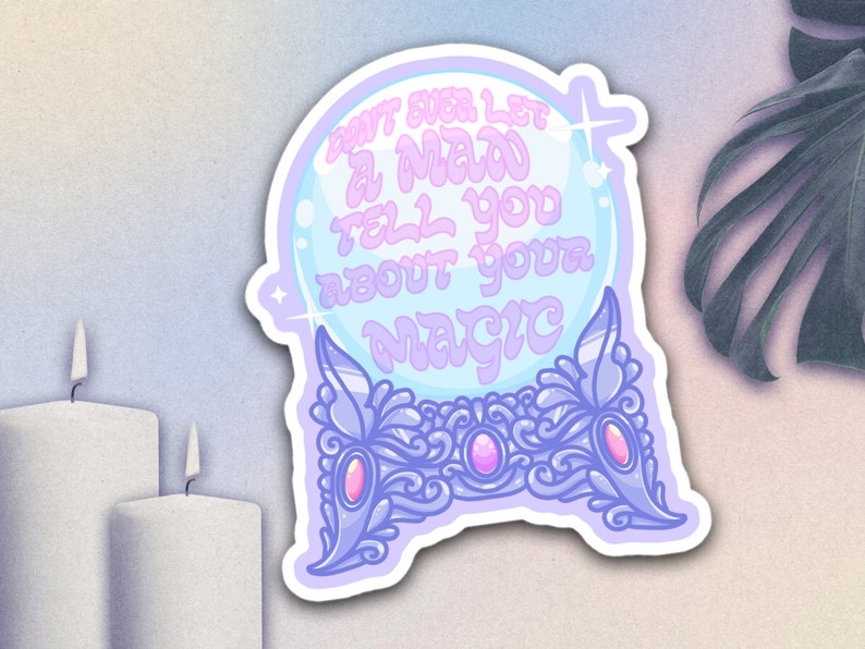 May include: A sticker featuring a crystal ball design with the text "DON'T EVER LET A MAN TELL YOU ABOUT YOUR MAGIC" in a whimsical font. The sticker has a light blue and purple color scheme with decorative accents.