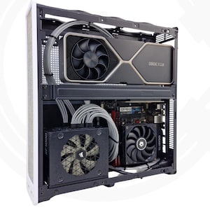 Puede incluir: Una carcasa de ordenador parcialmente ensamblada con varios componentes visibles. La carcasa es blanca con un interior negro, mostrando una tarjeta gráfica, una fuente de alimentación y ventiladores. El texto "CableSter For PC Enthusiast" es visible.