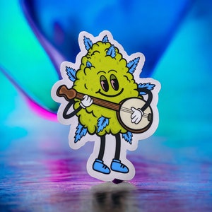 May include: A green cartoon character with blue leaves and a smiling face plays a banjo. The character is a sticker on a blue and purple background.