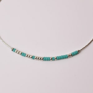 May include: A delicate silver chain necklace with turquoise beads.