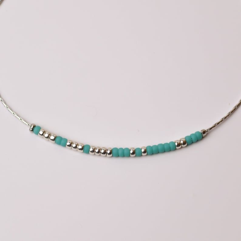 May include: A delicate silver chain necklace with turquoise beads.
