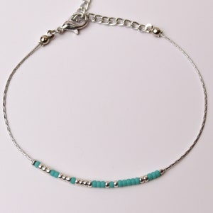 May include: A silver chain bracelet with a silver clasp and a row of turquoise and silver beads.