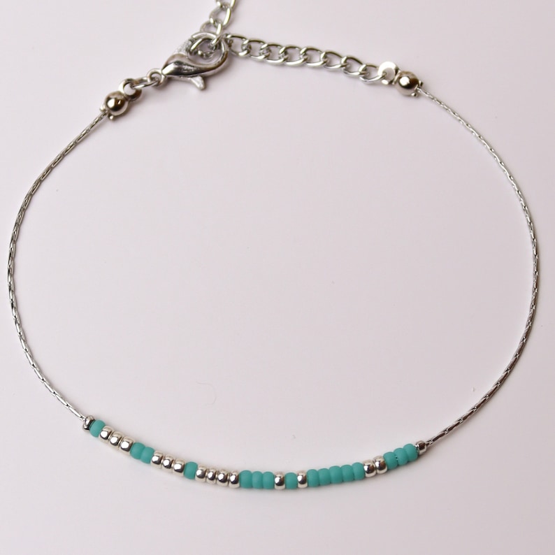 May include: A silver chain bracelet with a silver clasp and a row of turquoise and silver beads.