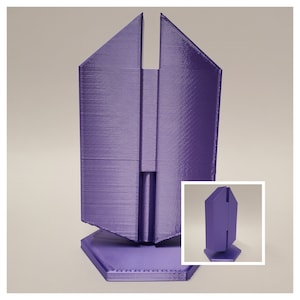 Könnte beinhalten: Ein violettes 3D-gedrucktes Modell eines Gebäudes mit sechseckiger Basis. Das Gebäude hat ein einzigartiges, geometrisches Design mit einem geteilten Dach.