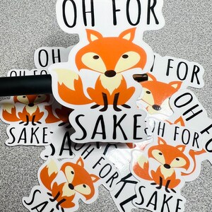 May include: A set of stickers featuring a cartoon fox with the text "Oh for sake". The stickers are white with black text and a cartoon fox with orange fur.