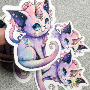 May include: Three iridescent holographic stickers of a purple and pink cat with a unicorn horn, stars, and a crescent moon design.