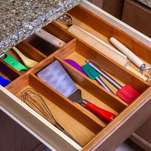 Drawer Organizer in drawer made from cherry. Utensils neatly organized. Granite countertop.