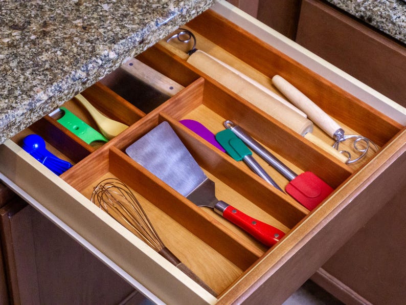 Drawer Organizer in drawer made from cherry. Utensils neatly organized. Granite countertop.
