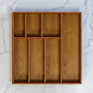 Cherry drawer organizer pictured on marble countertop. Empty, and displaying 7 compartments for cooking utensils.