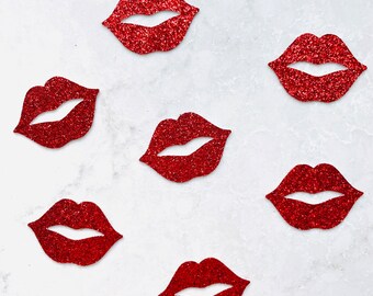 Könnte beinhalten: Sieben rote Glitzerlippen sind auf einer weißen Marmoroberfläche verstreut. Die Lippen haben alle die gleiche Größe und Form mit einem glänzenden, funkelnden Finish. Der Gesamteffekt ist verspielt und dekorativ.