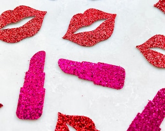 Könnte beinhalten: Draufsicht mit verstreuten glitzernden roten Lippen und pinkfarbenen Lippenstiftformen. Die Lippen und Lippenstifte sind in verschiedenen Größen und Ausrichtungen angeordnet und bilden ein dekoratives Muster. Der Glitzer erzeugt einen funkelnden Effekt.