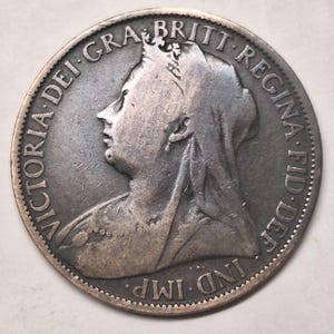 May include: A silver coin featuring a profile of a woman wearing a crown and veil. The coin's edge is inscribed with text, including "VICTORIA DEI GRA BRITT REGINA FID DEF IND IMP."