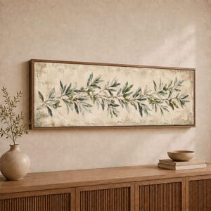 May include: A rectangular wall art piece featuring a horizontal olive branch illustration with green leaves and small olives on a distressed, textured beige background, enclosed within a thin, dark brown wooden frame.