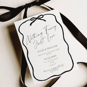 May include: A white wedding invitation with black text and a black border, tied with a black ribbon. The invitation reads "Nothing Fancy Just Love" and includes the names Kylie & William, date, time, and location.