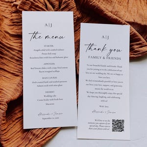 Puede incluir: Dos tarjetas de papelería de boda blancas con una elegante escritura negra. Una tarjeta dice "el menú" con una lista de platos. La otra tarjeta dice "Gracias, familia y amigos" con un mensaje y un código QR. El fondo es una tela naranja texturizada.