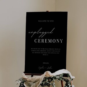 May include: Black sign with white text that reads "Welcome to our unplugged ceremony. We invite you to be fully present with us during our ceremony. Kindly switch off all devices and enjoy this special day with us. With love, Sophie & John."