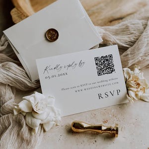 May include: A white RSVP card with a QR code and the text "Kindly reply by 05.01.20XX". An envelope with a gold wax seal is in the background. A gold stamp and white flowers are also present. The card prompts to scan to RSVP.