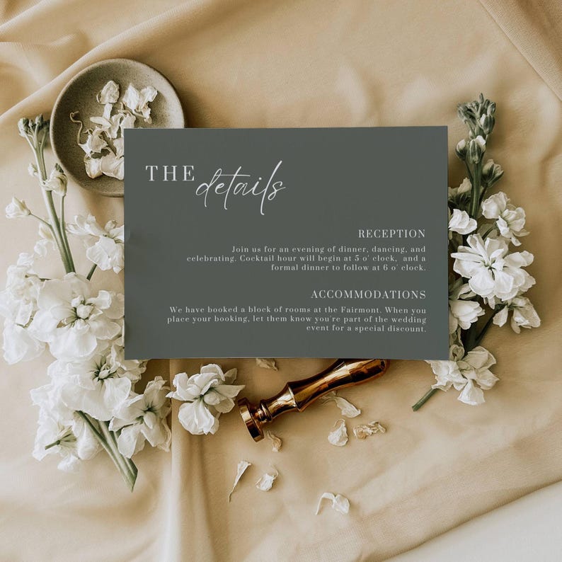 May include: A wedding details card in a dark gray color, with white floral accents and a gold wax seal. The card has the words "THE details" in elegant script, with information about the reception and accommodations.