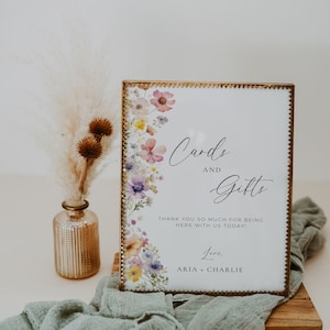 May include: A gold framed sign with a floral design and the text "Cards and Gifts" with the message "Thank you so much for being here with us today! Love, Aria + Charlie"