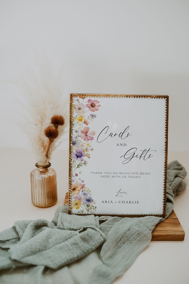 May include: A gold framed sign with a floral design and the text "Cards and Gifts" with the message "Thank you so much for being here with us today! Love, Aria + Charlie"