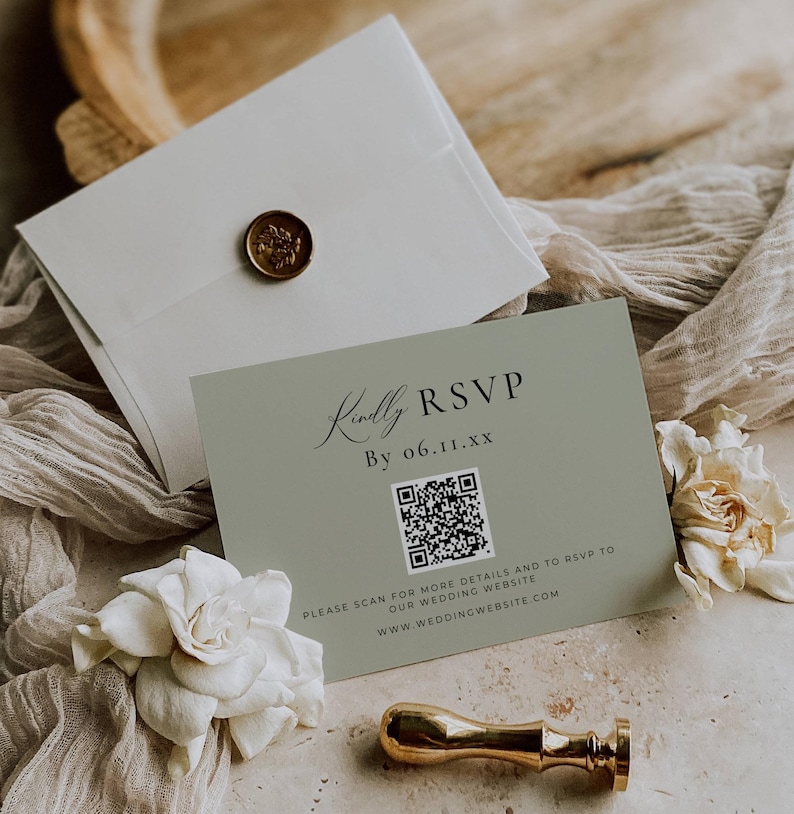 May include: A sage green RSVP card with the text "Kindly RSVP" and a QR code. The card is accompanied by a white envelope sealed with a gold wax stamp and a gold stamp handle. White flowers and fabric are in the background.