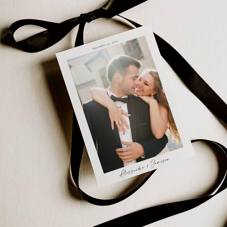 May include: A wedding photograph featuring a couple embracing, with the date "September 10, 20xx" and names "Alessandra & Jameson" printed on the photo. The photo is tied with a black ribbon.
