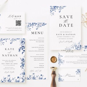 May include: A wedding stationery suite featuring a blue floral design. The cards include a save the date, invitation, RSVP, menu, and details card. The text on the cards includes the names Kate and Nathan, the wedding date, and the location. The cards are printed on a white background with a blue floral border.