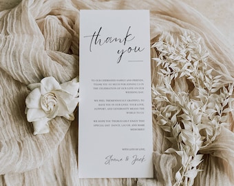 May include: A white thank you card with black calligraphy that reads "thank you" and a message expressing gratitude to guests for attending a wedding. The card is on a beige fabric background with white flowers.