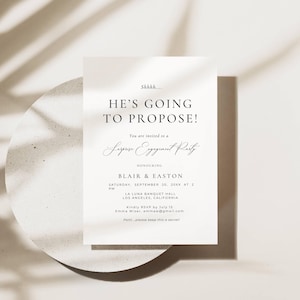 May include: A white rectangular invitation card with black text that reads: Shhhh.... HE'S GOING TO PROPOSE! You are invited to a Surprise Engagement Party HONOURING BLAIR & EASTON SATURDAY, SEPTEMBER 20, 20XX AT 2 PM LA LUNA BANQUET HALL LOS ANGELES, CALIFORNIA.
