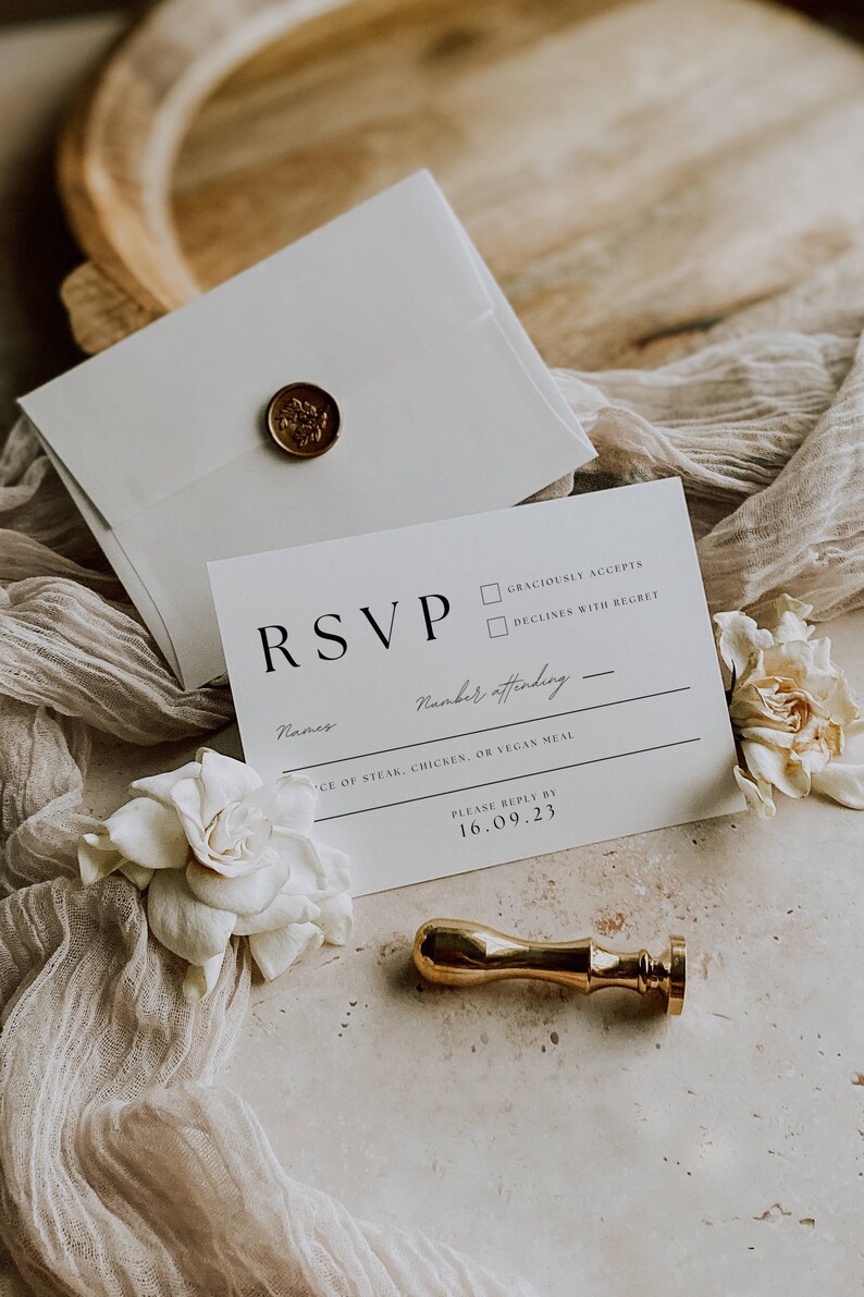 May include: A white RSVP card with a gold wax seal. The card has a black RSVP heading, a line for names, a line for the number of people attending, a line for meal choices, and a line for the RSVP deadline. The deadline is 16.09.23.