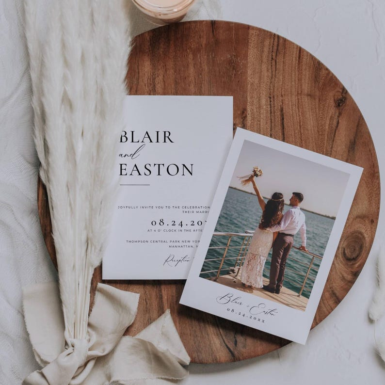 May include: Wedding invitation suite featuring a photo card and invitation. The invitation reads "Blair and Easton" with event details. The photo card displays a couple on a boat. The suite is on a wooden tray with decorative elements.