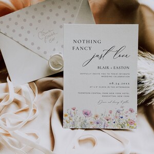May include: A wedding invitation with a floral design and the text "Nothing Fancy Just Love" with the names Blair and Easton, the date 08.24.20XX, and the location Thompson Central Park New York Hotel, Manhattan, New York.
