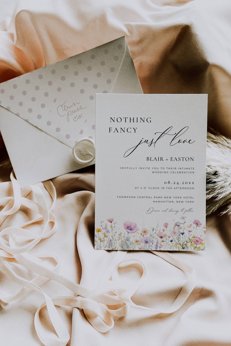 May include: A wedding invitation with a floral design and the text "Nothing Fancy Just Love" with the names Blair and Easton, the date 08.24.20XX, and the location Thompson Central Park New York Hotel, Manhattan, New York.