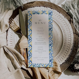 Pode incluir: Um cartão de menu de casamento com um design estampado em azul, amarelo e branco. O menu inclui entrada, prato principal, sobremesa e os nomes Alexia e Jackson com a data 05.17.20xx.