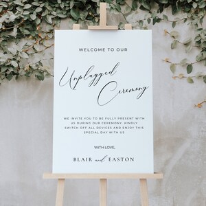 May include: White sign with black text on an easel. The sign reads "Welcome to our Unplugged Ceremony. We invite you to be fully present with us during our ceremony. Kindly switch off all devices and enjoy this special day with us. With love, Blair and Easton."