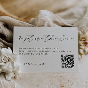 May include: White card with black text that reads "Capture the Cove". Below the text is a QR code and the text "Please share your photos with us. Simply scan the code with your smartphone and upload your photos. ELIANA + JAMES".