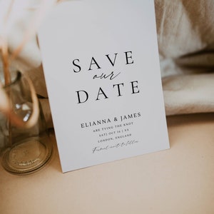 May include: Save the date card with a white background and black text. The card says "Save our date" and includes the names "Elianna & James" and the date "Sat) Oct 16 | XX". The card also includes the location "London, England" and the text "Formal invite to follow".