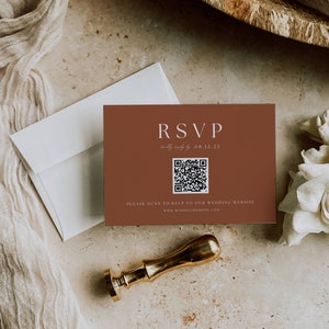 May include: A brown RSVP card with a QR code and the text "RSVP kindly reply by 08.12.23" and "PLEASE SCAN TO RSVP TO OUR WEDDING WEBSITE www.weddingwebsite.com"