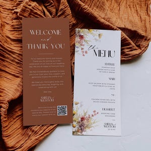May include: Two wedding menu cards with floral accents and text. One card says "Welcome and Thank You" and the other says "The Menu" with a list of dishes. The cards are brown and white with a QR code.