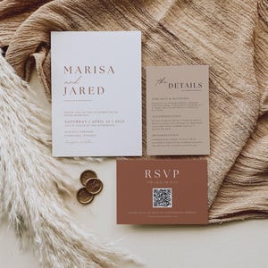 May include: A wedding invitation suite featuring a main invitation, details card, and RSVP card. The main invitation is white with brown text, including the names "Marisa and Jared" and the wedding date. The RSVP card is a terracotta color.